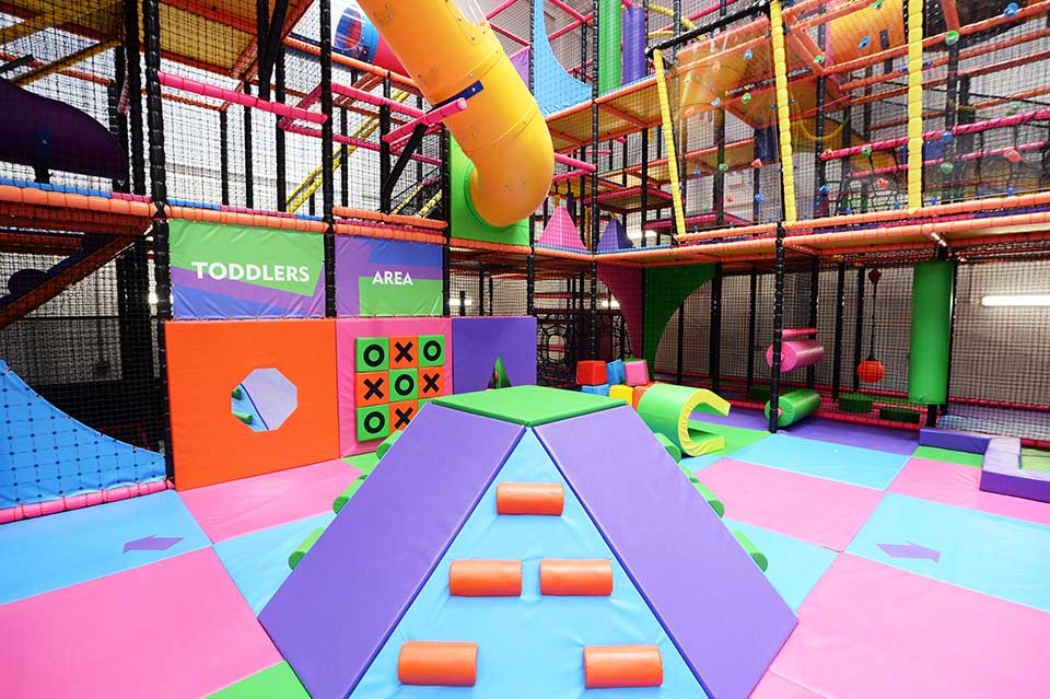 Bright and colourful indoor play area featuring climbing structures, slides, and soft play equipment for children, designed for fun and active play.