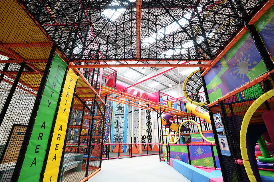 Indoor adventure playground featuring vibrant climbing structures, slides, and colourful walls designed for children's play and exploration.