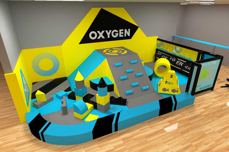 Indoor play area featuring a vibrant blue and yellow obstacle course with various climbing structures, foam blocks, and a large slide, designed for children's active play and fitness at Oxygen.